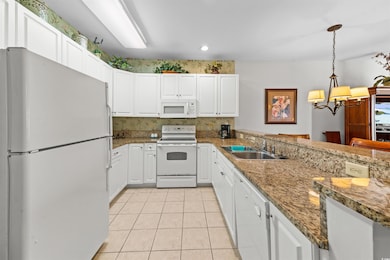 Kitchen with white cabinetry, sink, pendant lighti
