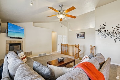 Living area featuring lofted ceiling, a ceiling fan, and a fireplace