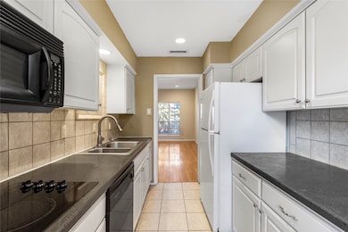 Kitchen featuring black appliances, dark countertops, white cabinets, and recessed lighting