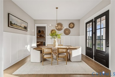 Dining space with a decorative wall, wood finished floors, and a wainscoted wall