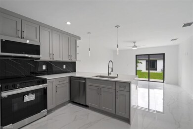 Kitchen featuring appliances with stainless steel finishes, light marble finish floors, gray cabinetry, backsplash, and pendant lighting