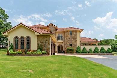 Mediterranean / spanish-style home with curved driveway, stone siding, a front yard, stucco siding, and a tile roof