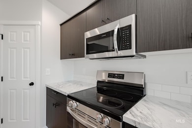Kitchen with appliances with stainless steel finishes, light countertops, dark brown cabinetry, and modern cabinets