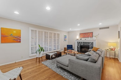 Living room with recessed lighting, a premium fireplace, light wood-type flooring, and ornamental molding