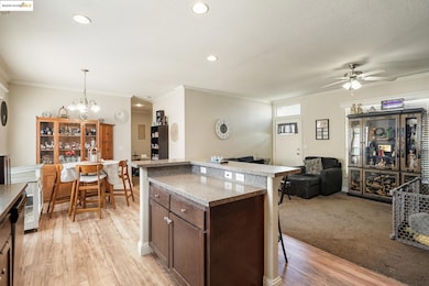 Kitchen with dark brown cabinetry, a kitchen bar, open floor plan, decorative light fixtures, and ornamental molding