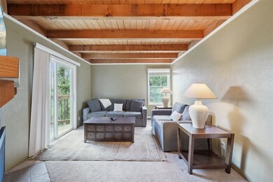 Living area with a wood ceiling with exposed beams and baseboard heating