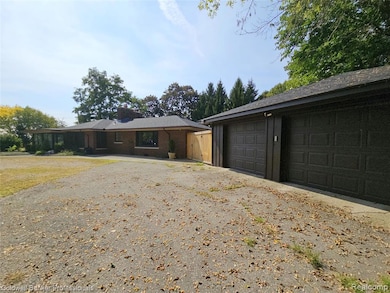 View of front of property featuring a garage, brick siding, and a chimney