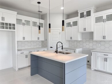 Kitchen with sink, white cabinets, tasteful backsplash, and a center island with sink
