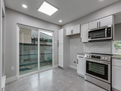 Kitchen with backsplash, white cabinetry, and stai