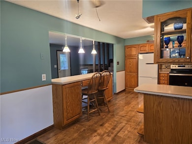 Kitchen featuring brown cabinets, stainless steel electric range oven, dark wood-style floors, and light countertops