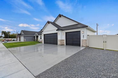 View of front of house with a gate, concrete driveway, stone siding, a garage, and roof with shingles
