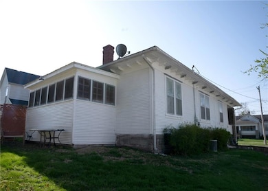 View of side of home with a yard, central air condition unit, a sunroom, and a chimney