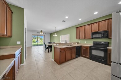Kitchen featuring black appliances, light tile patterned floors, light countertops, a peninsula, and decorative light fixtures