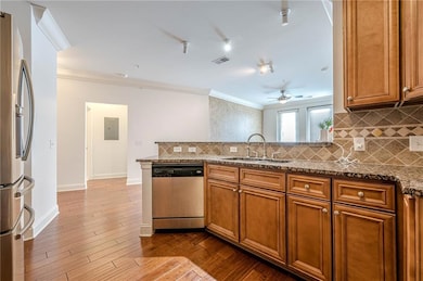 Kitchen featuring appliances with stainless steel finishes, a sink, crown molding, brown cabinetry, and ceiling fan