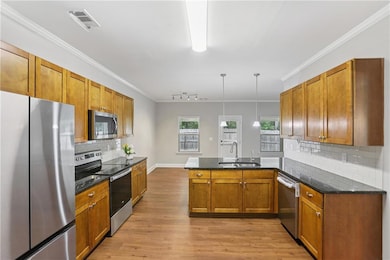 Kitchen with stainless steel appliances, a sink, brown cabinets, a peninsula, and light wood-style floors