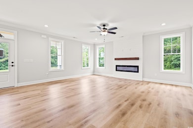 Unfurnished living room featuring crown molding, recessed lighting, light wood-style flooring, ceiling fan, and a glass covered fireplace