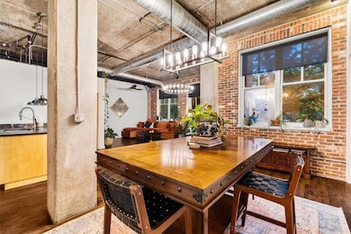 Dining area featuring brick wall, dark wood-style flooring, and a chandelier