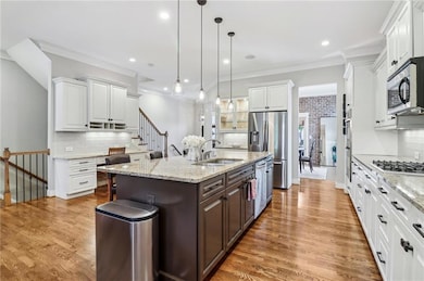 Kitchen featuring a sink, stainless steel appliances, white cabinetry, decorative backsplash, and dark brown cabinets