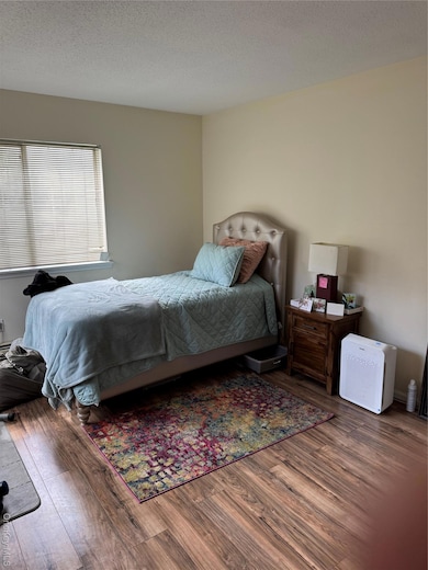 Bedroom with a textured ceiling and wood finished floors