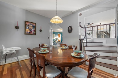 Dining area featuring wood finished floors, stairs, and a ceiling fan