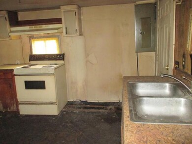 Kitchen with electric stove, electric panel, under cabinet range hood, and light countertops