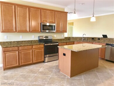 Kitchen featuring appliances with stainless steel finishes, crown molding, light tile patterned floors, dark stone counters, and brown cabinetry