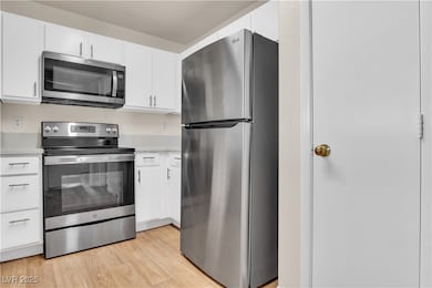Kitchen featuring stainless steel appliances, white cabinets, and light wood-type flooring