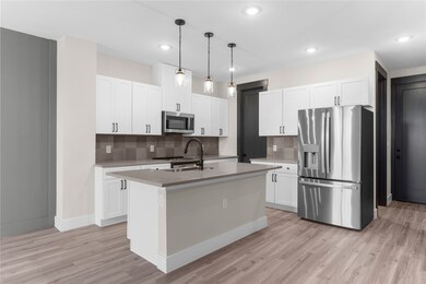 Kitchen with stainless steel appliances, white cabinetry, pendant lighting, light wood finished floors, and recessed lighting