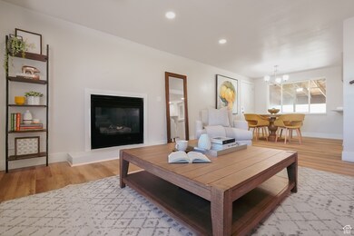 Living room with light wood-type flooring, a chandelier, recessed lighting, and a glass covered fireplace