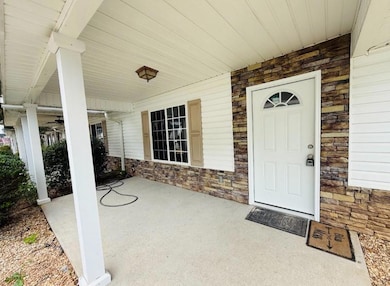 Property entrance with stone siding and a porch