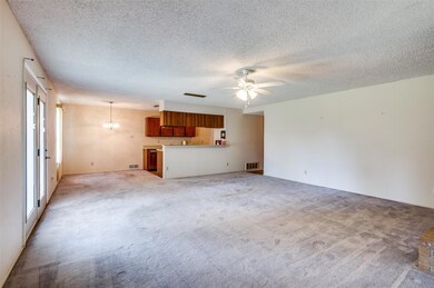 Unfurnished living room featuring ceiling fan, a textured ceiling, and light carpet