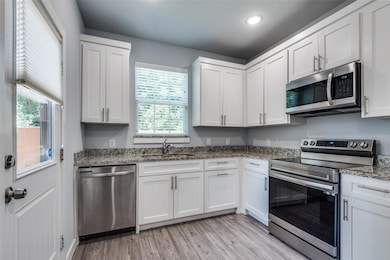 Kitchen featuring white cabinetry, sink, light sto