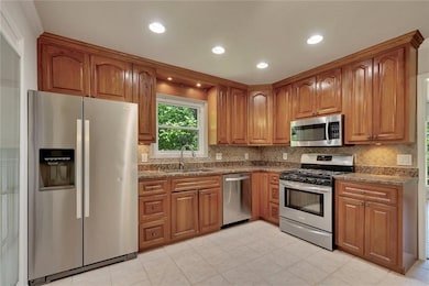 Kitchen with stainless steel appliances, brown cabinets, backsplash, and recessed lighting
