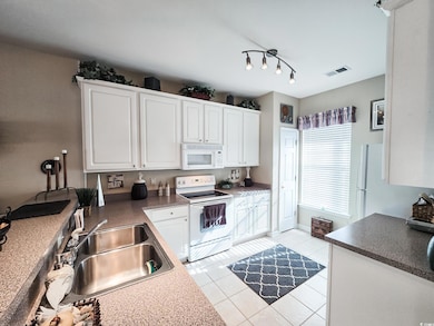 Kitchen featuring sink, white appliances, light ti