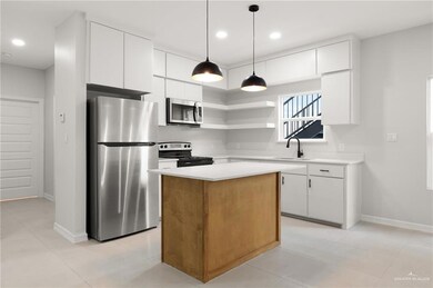 Kitchen with stainless steel appliances, a kitchen island, white cabinets, light countertops, and decorative light fixtures