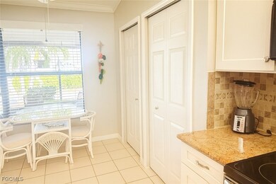 Kitchen with backsplash, white cabinetry, light tile patterned flooring, light stone counters, and crown molding