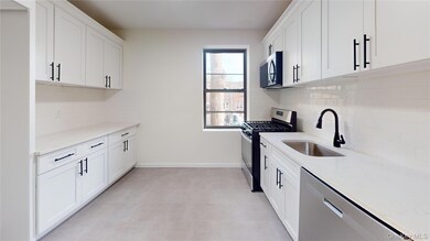 Kitchen with stainless steel appliances, light stone counters, and white cabinets