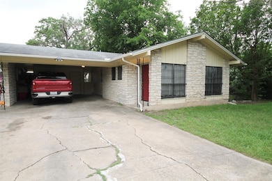 Ranch-style home featuring stone siding, driveway, and a front lawn