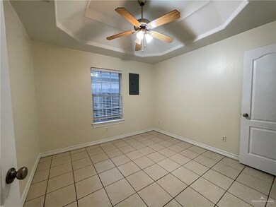 Unfurnished room with a raised ceiling, electric panel, light tile patterned floors, and a ceiling fan