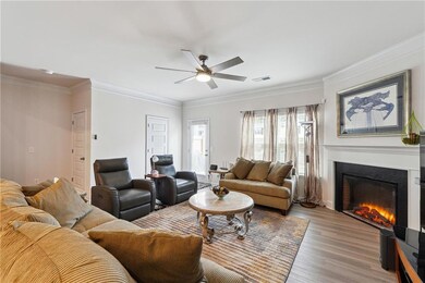 Living room with crown molding, ceiling fan, and l