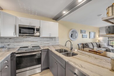 Kitchen featuring gray cabinets, stainless steel appliances, open floor plan, tasteful backsplash, and light stone counters