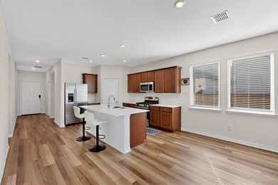 Kitchen featuring a breakfast bar, stainless steel appliances, a center island with sink, light wood-style floors, and recessed lighting