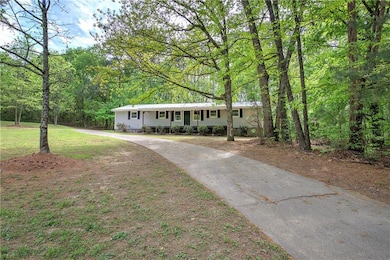 Ranch-style home with asphalt driveway and a view of trees