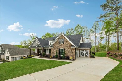 Craftsman-style home with stone siding, driveway, a front lawn, and an attached garage