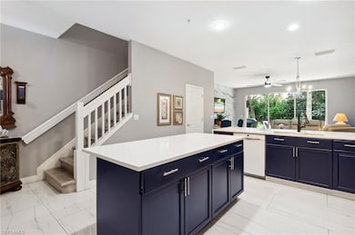 Kitchen with white dishwasher, blue cabinetry, light marble finish floors, open floor plan, and a center island