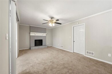 Unfurnished living room featuring ornamental molding, light carpet, a fireplace, and a ceiling fan