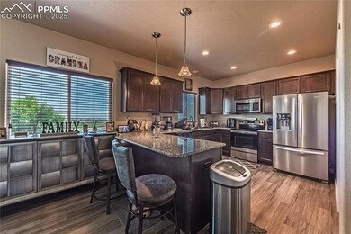 Kitchen with appliances with stainless steel finishes, dark brown cabinetry, a peninsula, light wood-type flooring, and recessed lighting