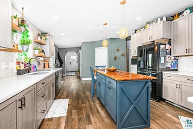 Kitchen featuring a sink, black fridge, wooden counters, open shelves, and backsplash