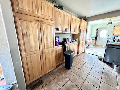 Kitchen with light tile patterned flooring, light brown cabinetry, and a textured ceiling