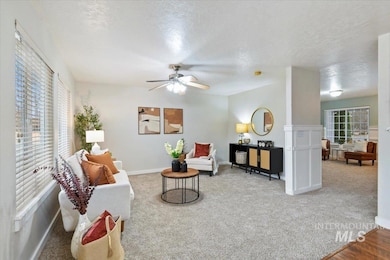 Living area featuring a textured ceiling, light colored carpet, and ceiling fan